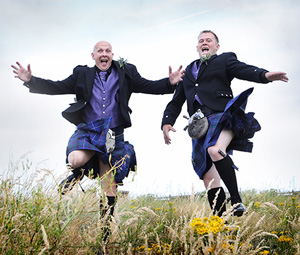 Two men jumping in kilts